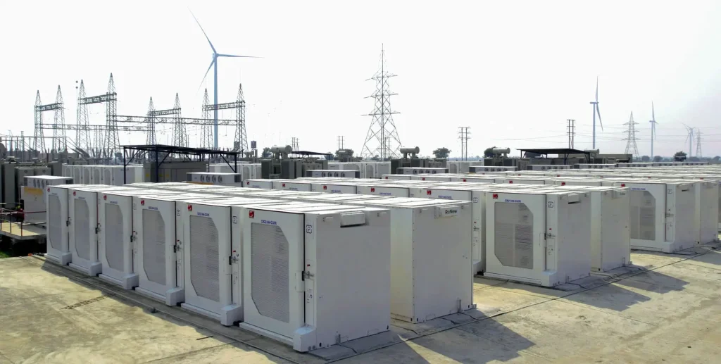 Renewable energy battery storage system with solar panels and wind turbines powering a grid.
